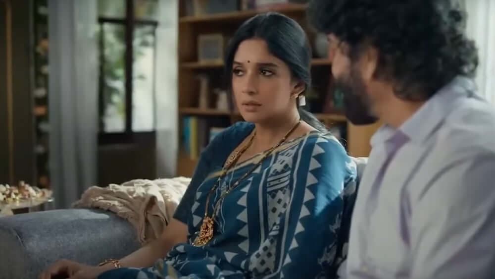 A woman in a blue sari in conversation with a man at home, from the Kalyan Jewellers film